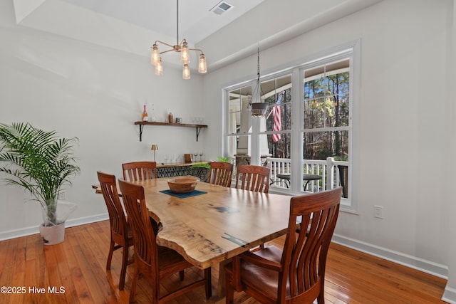 dining room with an inviting chandelier, wood-type flooring, visible vents, and baseboards