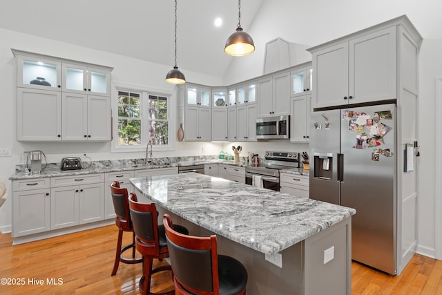 kitchen with light wood-type flooring, appliances with stainless steel finishes, pendant lighting, and lofted ceiling