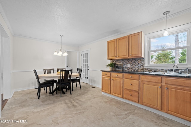 kitchen with ornamental molding, dark countertops, a sink, and backsplash