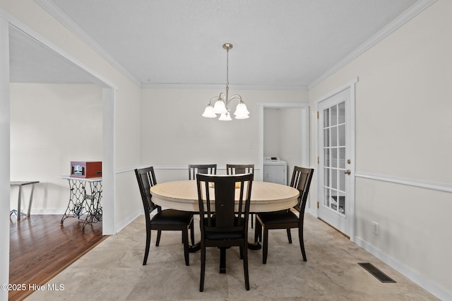 dining space featuring visible vents, washer / clothes dryer, a chandelier, and crown molding