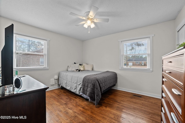 bedroom featuring multiple windows, wood finished floors, visible vents, and baseboards