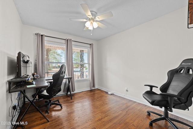 home office featuring a ceiling fan, a textured ceiling, baseboards, and wood finished floors