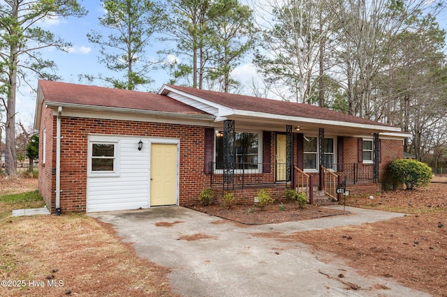 single story home with driveway, covered porch, and brick siding