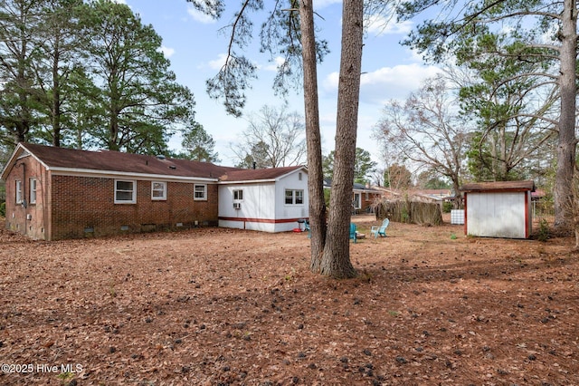 exterior space with a storage shed, brick siding, crawl space, and an outdoor structure