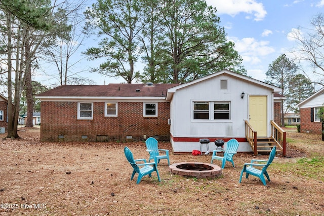 rear view of house with entry steps, brick siding, crawl space, and a fire pit