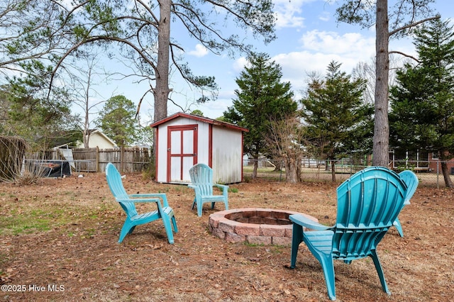 view of yard featuring a storage unit, an outdoor fire pit, an outdoor structure, and fence