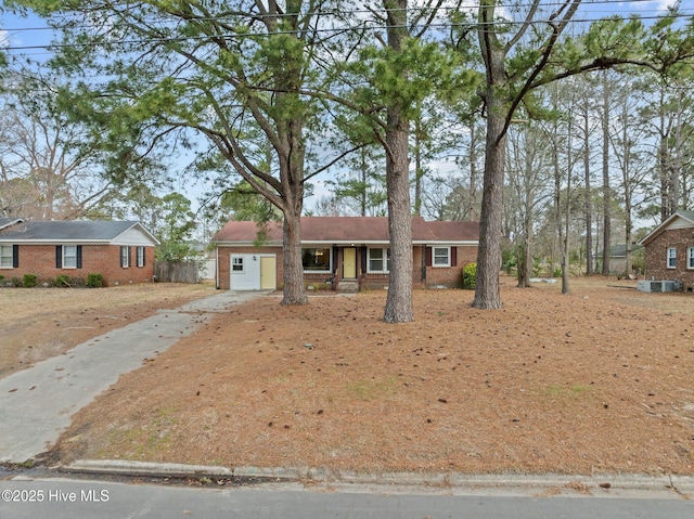 ranch-style house featuring a garage, brick siding, and driveway