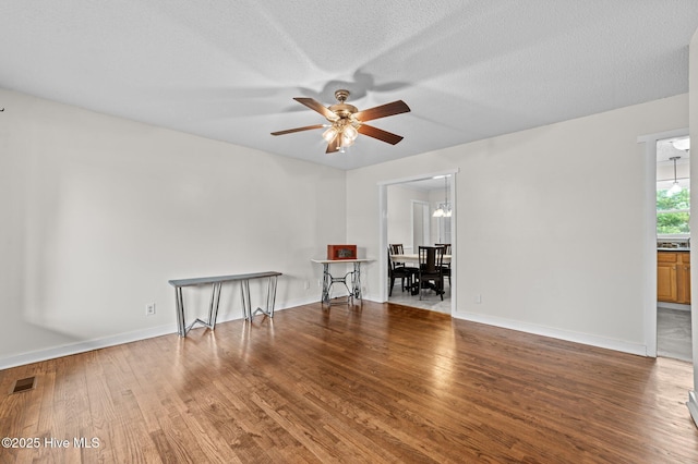 unfurnished room featuring baseboards, a textured ceiling, visible vents, and wood finished floors