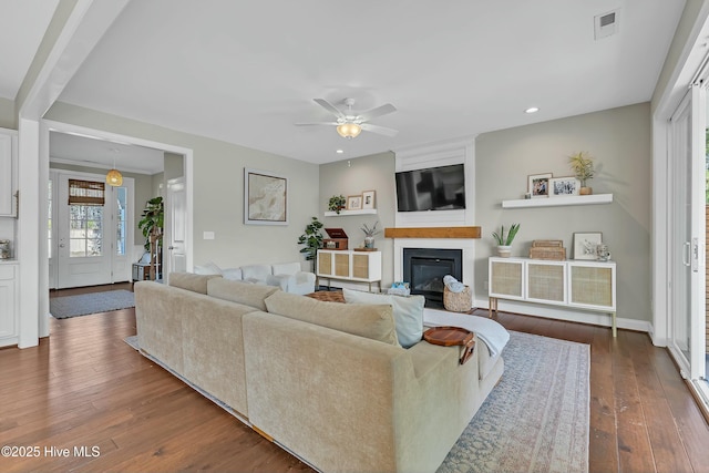 living area featuring hardwood / wood-style flooring, a fireplace, visible vents, and ceiling fan