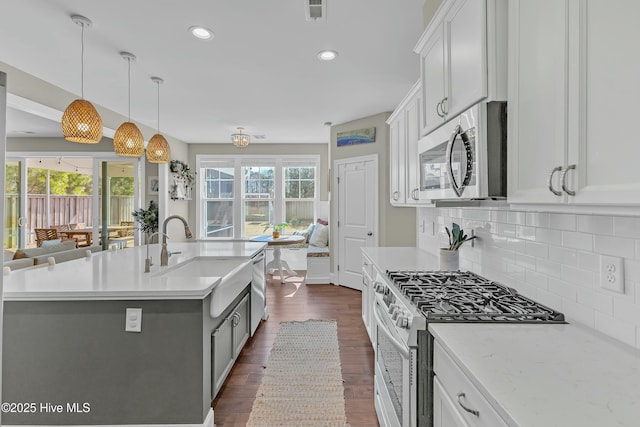 kitchen with visible vents, dark wood-style flooring, a sink, decorative backsplash, and stainless steel appliances