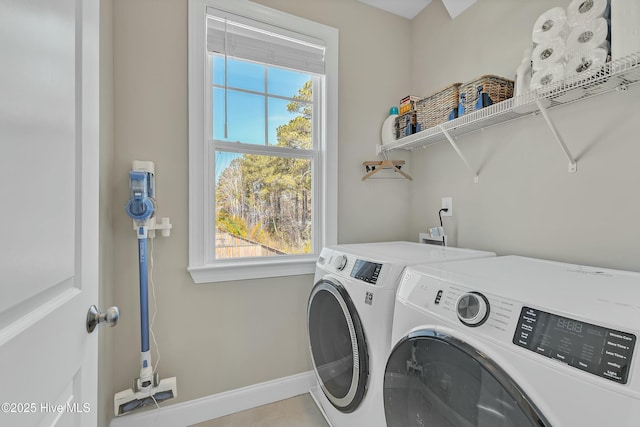 washroom with baseboards, separate washer and dryer, and laundry area