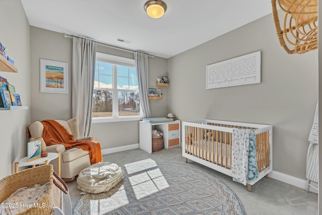 bedroom featuring a crib, carpet, visible vents, and baseboards