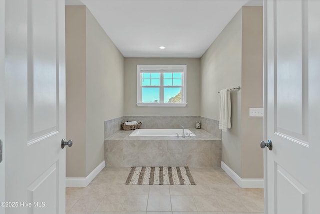 bathroom featuring tile patterned flooring, a bath, and baseboards