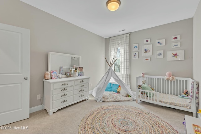 bedroom featuring visible vents, a nursery area, carpet, and baseboards