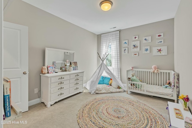 bedroom featuring visible vents, baseboards, a nursery area, and carpet floors