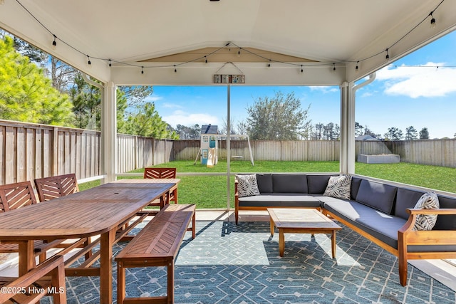 view of patio with outdoor dining space, outdoor lounge area, a playground, and a fenced backyard