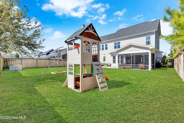 view of playground featuring a lawn, a fenced backyard, and a sunroom