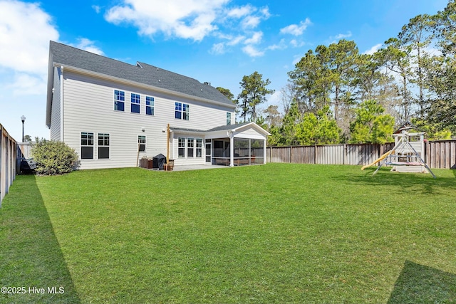 rear view of property with a playground, a yard, a fenced backyard, and a sunroom