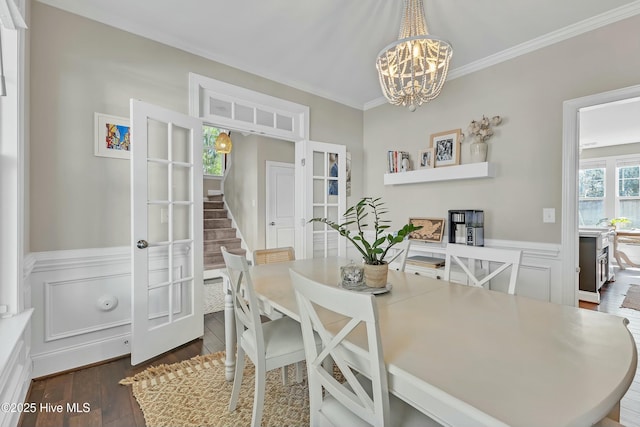 dining area with ornamental molding, dark wood-style floors, stairway, an inviting chandelier, and wainscoting