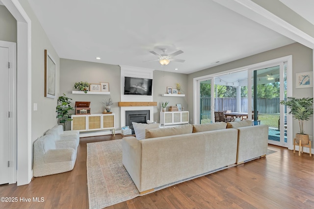 living area featuring a ceiling fan, recessed lighting, wood finished floors, and a large fireplace