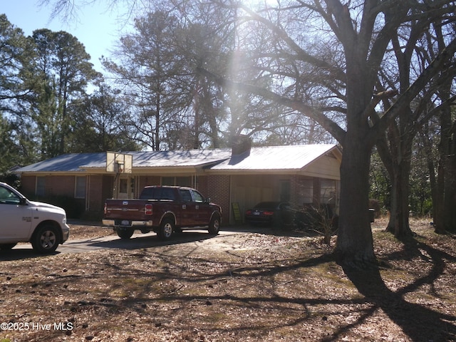 view of property exterior featuring metal roof, brick siding, and an attached carport