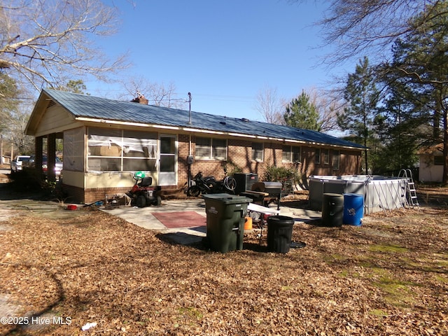 rear view of property with a sunroom, a patio area, brick siding, and a chimney