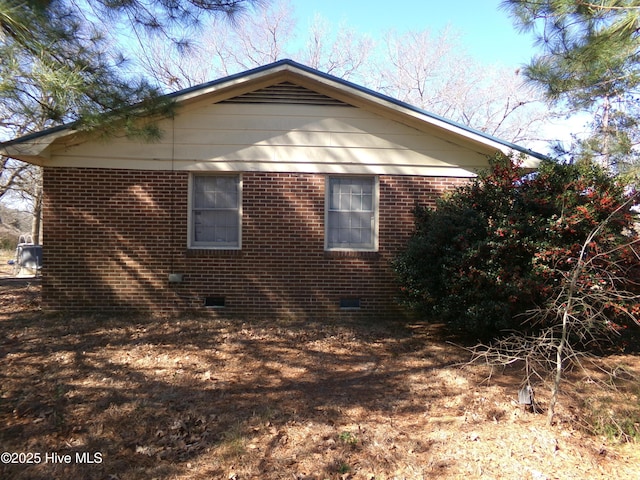 view of side of home with crawl space and brick siding