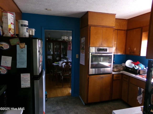 kitchen featuring brown cabinets, stainless steel appliances, light countertops, a textured ceiling, and a chandelier