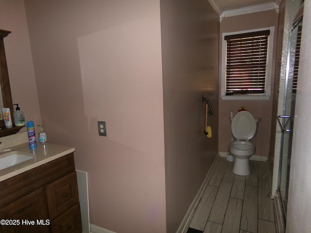 full bathroom with toilet, wood finished floors, vanity, baseboards, and ornamental molding