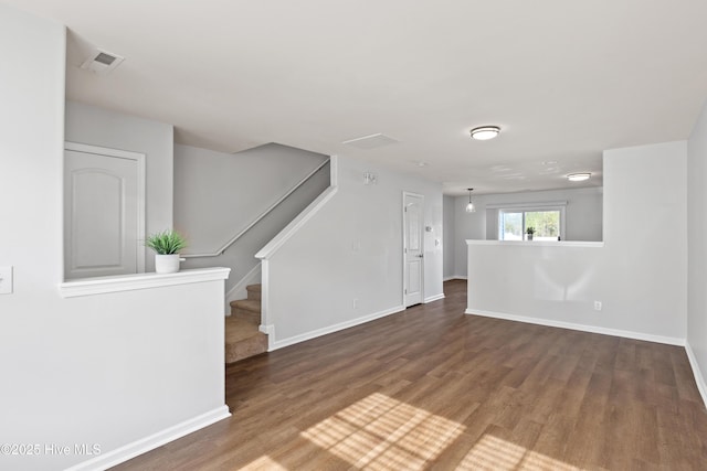 spare room featuring baseboards, visible vents, stairway, and wood finished floors