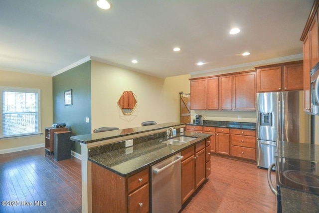 kitchen with dark wood finished floors, ornamental molding, appliances with stainless steel finishes, and a sink