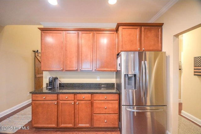 kitchen featuring dark stone counters, stainless steel fridge with ice dispenser, baseboards, and ornamental molding