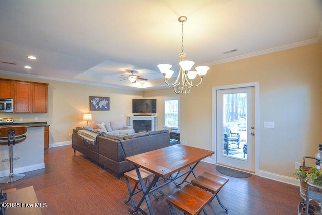 dining space featuring dark wood-style floors, a fireplace, baseboards, and ornamental molding