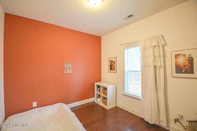 bedroom featuring visible vents, multiple windows, baseboards, and wood finished floors