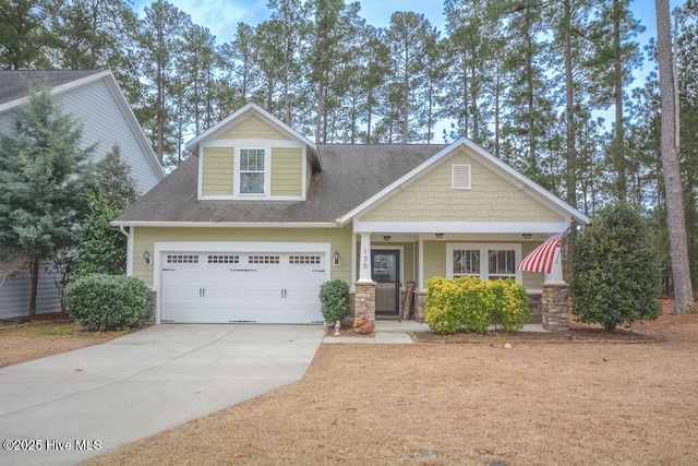 craftsman inspired home featuring covered porch, driveway, and a shingled roof