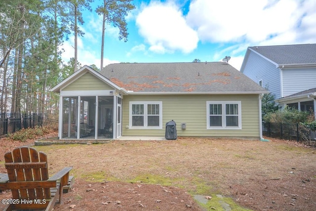 rear view of property featuring a lawn, roof with shingles, a fenced backyard, and a sunroom