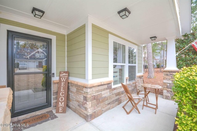 doorway to property featuring brick siding and a porch