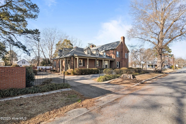 view of front of home with a chimney, fence, and brick siding