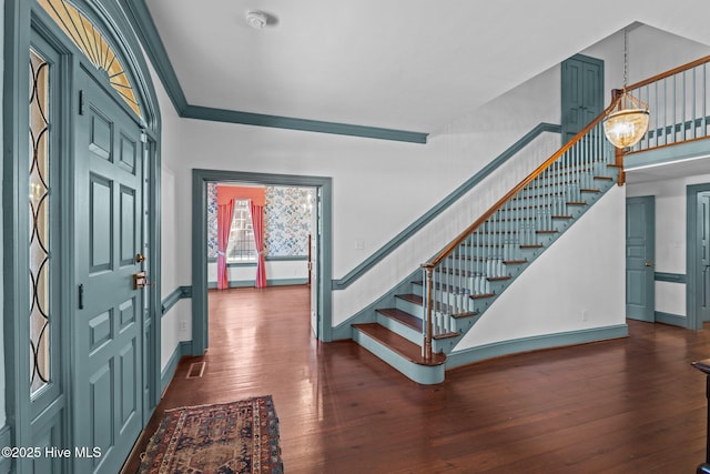 foyer featuring visible vents, baseboards, ornamental molding, stairway, and dark wood finished floors