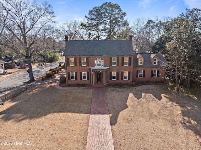 view of front of house with brick siding and a chimney