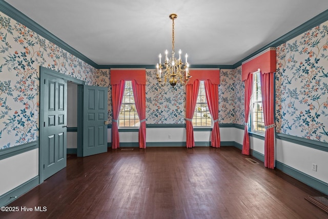 unfurnished dining area featuring wood finished floors, a notable chandelier, crown molding, and wallpapered walls