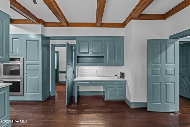 kitchen featuring dark wood-style floors, backsplash, light countertops, and stainless steel double oven