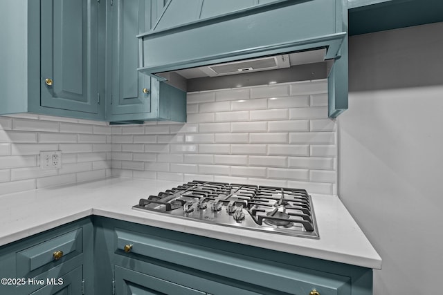 kitchen featuring custom range hood, stainless steel gas cooktop, decorative backsplash, and light countertops