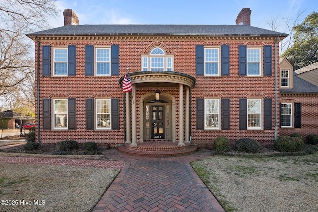 colonial-style house featuring brick siding and a chimney