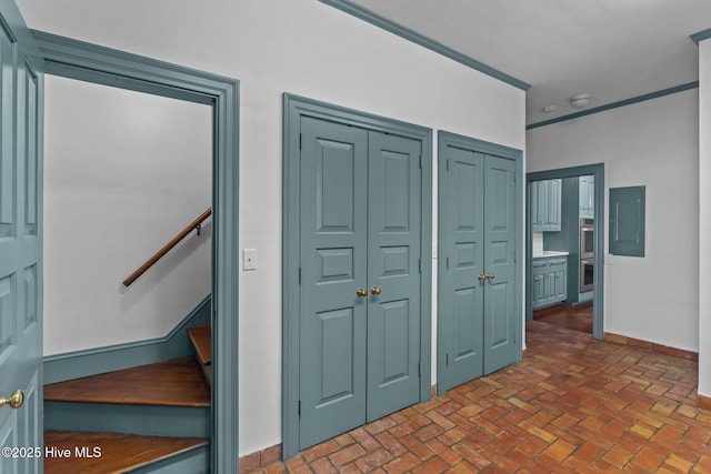 interior space featuring baseboards, brick floor, electric panel, and multiple closets