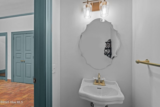 bathroom featuring brick floor and a sink