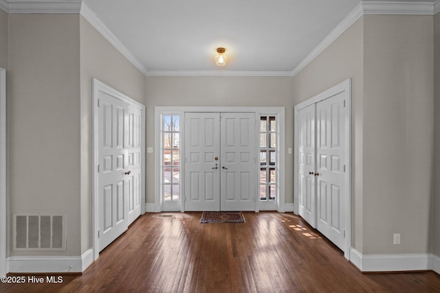 foyer with wood-type flooring, visible vents, crown molding, and baseboards