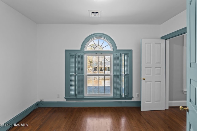 spare room with dark wood-style floors, baseboards, and visible vents