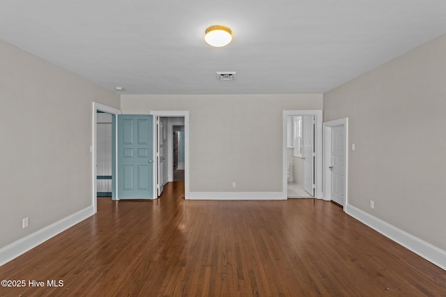 unfurnished bedroom featuring dark wood-style floors, visible vents, a spacious closet, and baseboards