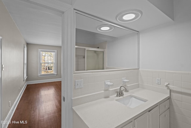 bathroom featuring tile walls, a stall shower, vanity, wood finished floors, and baseboards